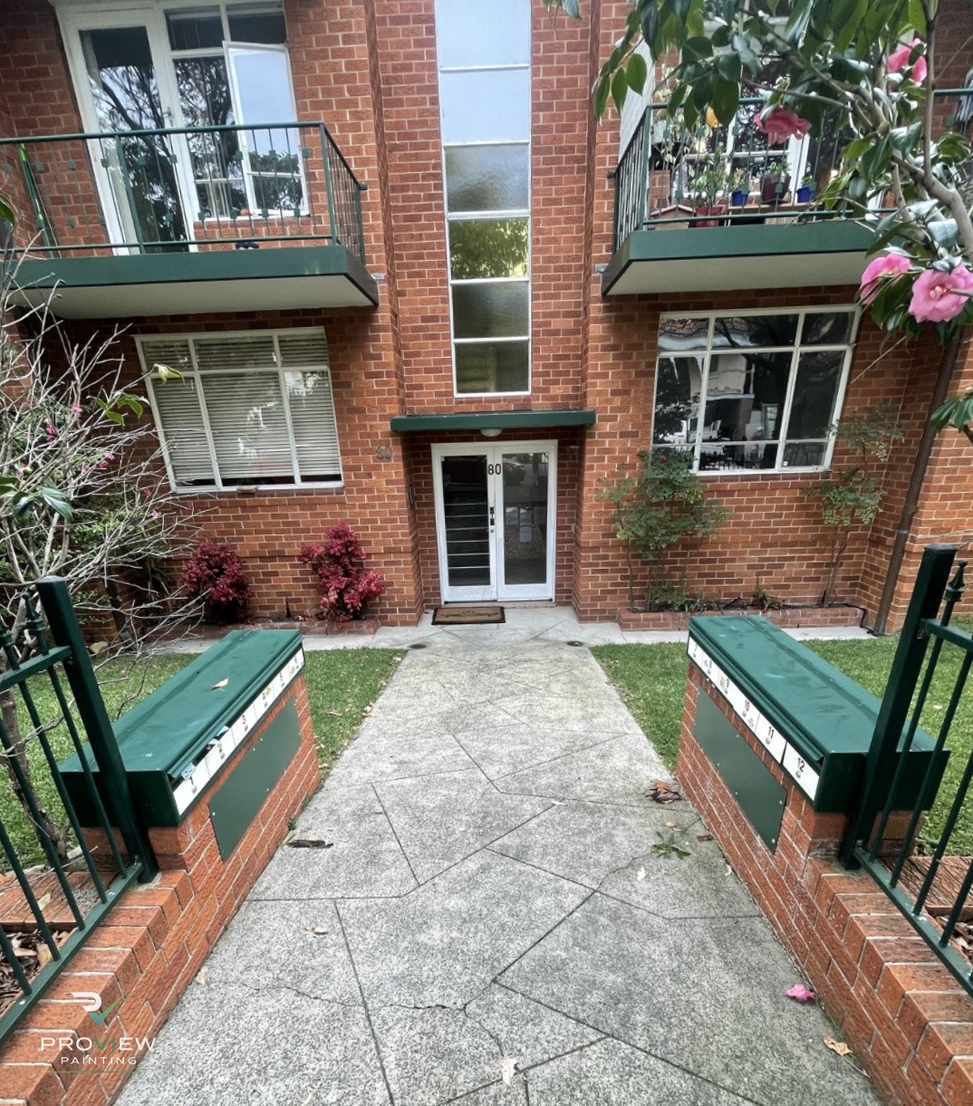 Before — common-area entry, balconies and mailboxes in the old green scheme